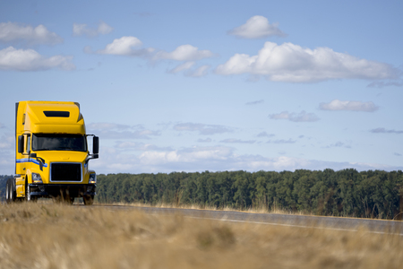 Big rig yellow semi truck tractor without of semi trailer going on the road with another traffic along the river to pick up the trailer with cargo and delivery it to destination warehouse on the timeの写真素材
