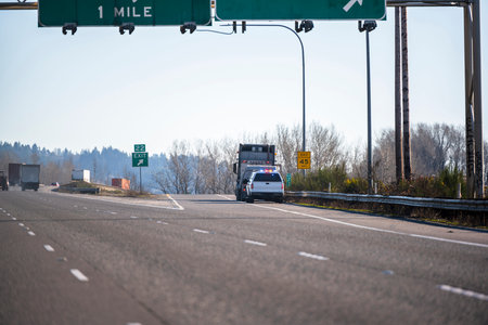 A patrol policeman on a truck with flashing lights stopped a big rig semi truck with flat bed semi...