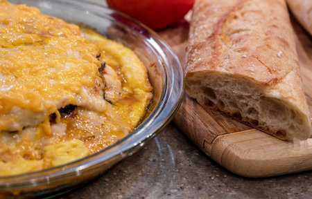 Baking in a glass tray in electrical oven a layered meat pie with mushrooms and vegetables, covered...