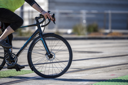 A woman cyclist in leggings crosses the tram rails on a bicycle, preferring an active way of relaxation, helping her to keep herself in good shape, in a good fit and enjoy life in sunny dayの写真素材