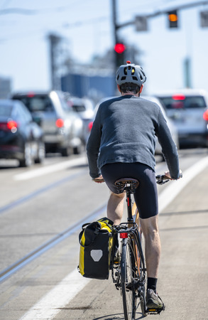 Cyclist cycling pedals a bicycle and rides uphill along a dedicated bicycle path preferring active healthy lifestyle and alternative eco-friendly transport in order to preserve the environmentの写真素材
