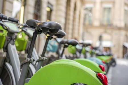 Street transportation green hybrid public rent bicycles for traveling around the Paris stand in row on rental network parking lot waiting for cyclists ready to make an exciting active tripの写真素材