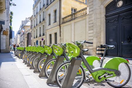 Street transportation green public rent bicycles with basket for traveling around the Paris city stand in row on rental network parking lot waiting for cyclists ready to make an exciting bike tripの写真素材