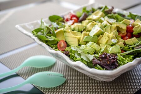 Nutritious low-calorie organic vegetable salad made from green leaves and tomato and avocado seasoned with olive oil will help the body get the necessary vitamins and normalize the stomach workの写真素材
