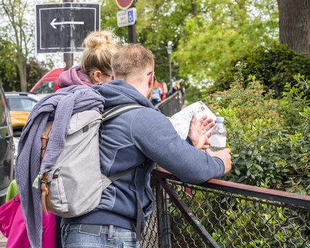 Tourist couple husband and wife with backpacks and spare clothes study the map of the city, determining the route of their movement to the sights and famous architectural and historical landmarksの写真素材