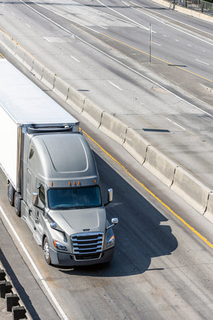Big rig gray long haul bonnet professional heavy-duty semi truck transporting commercial cargo in...