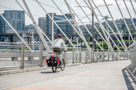 Man Cyclist in sports outfit rides a bicycle on the Tilikum Crossing Bridge. The use of a bicycle as...