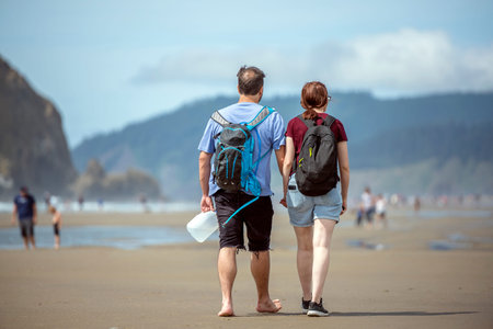 Young couple are walking along the shore of the Northwest Pacific Ocean holding hands and breathing...