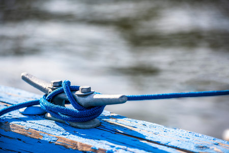 The metal bracket with two bolts is bolted to the wooden beam of the pier for mooring boats or...