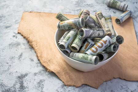 Cash banknotes of American dollar bills of various values stand on the table as a metaphor for eating up life values and a reminder of the frailty of money in exchange for a full-fledged lifeの素材 [FY310134939599]