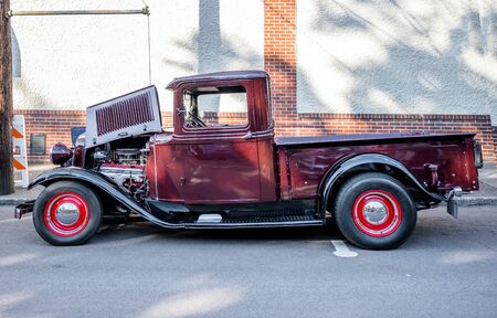 Elegant Burgundy old vintage retro truck with large convex wings and headlights and open hood with powerful engine standing on an improvised street exhibition of retro cars in a provincial townの写真素材