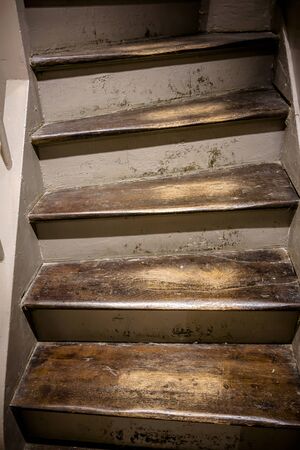 An old staircase with wooden steps with a varnish worn off from long use, which covered the steps, and recesses in the surface of the steps, formed from shuffling feetの写真素材