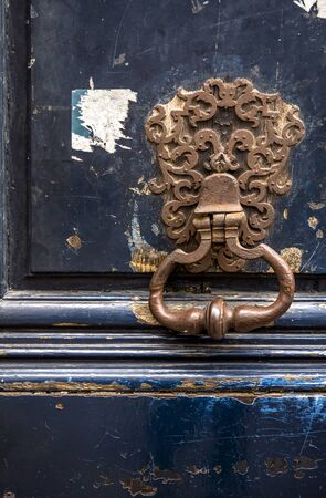 Fragment of old painted wooden door with a peeling paint and rusty forged metal handle doorknob as a symbol of communication and protection of private interests and safe personal life informationの写真素材