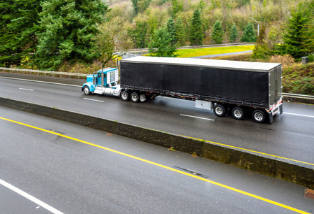 Big rig blue day cab semi truck for local deliveries transporting commercial cargo in black dry van...
