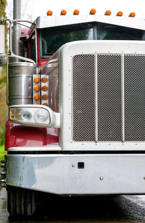 Big rig bonnet diesel industrial wet red semi truck chrome accessories standing on the street road parking in raining weather waiting for cargo load for next deliveryの写真素材