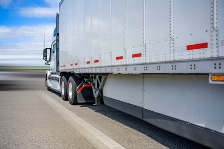 Classic white powerful long haul diesel big rig semi truck with high cab transporting cargo in dry...