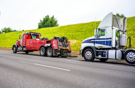 Powerful heavy-duty big rig mobile tow semi truck with emergency lights and towing equipment prepare...