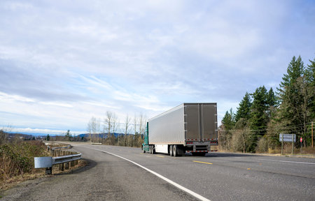 Loaded industrial green big rig semi truck transporting frozen commercial cargo in shine stainless...
