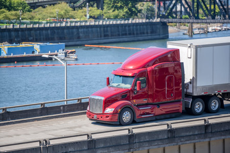 Red industrial grade diesel big rig semi truck with low cab for best aerodynamics transporting...