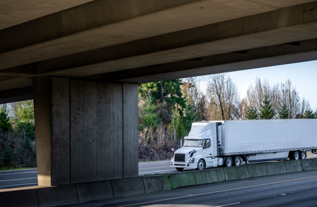 Big rig industrial white day cab semi truck tractor transporting frozen commercial cargo in...