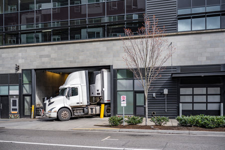 Commercial white big rig day cab semi truck with roof spoiler and refrigerator semi trailer make a...
