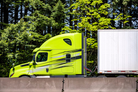 Bright lime big rig long haul industrial semi truck tractor with roof spoiler transporting cargo in...