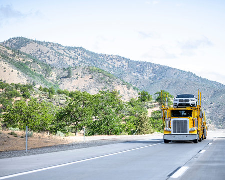 Yellow professional industrial big rig car hauler semi truck transporting cars on the modular semi...