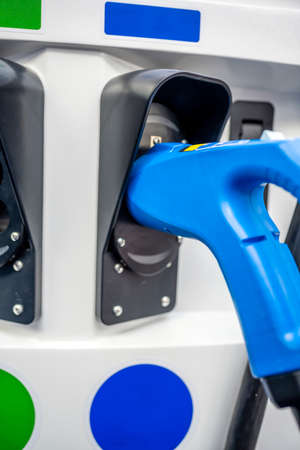 The electric car charger gun with power supply cable is inserted into the connector of the power supply charging station unit of the refueling environmentally friendly carの写真素材