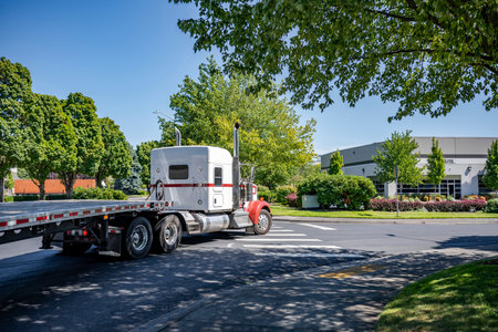 Classic white bonnet American industrial big rig semi truck tractor transporting empty flat bed semi...