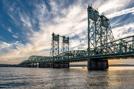 Arched transportation truss Columbia River Interstate Drawbridge over the Columbia River through which Interstate I-5 highway passes along entire western coast of America at evening with cloud skyの写真素材