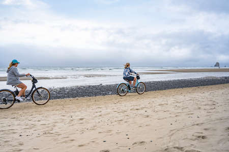Two middle-aged women amateur cyclists rides bicycles traveling on the cost line along the Northwest Pacific Ocean preferring an active healthy lifestyle tempering the body in great summer weatherの写真素材