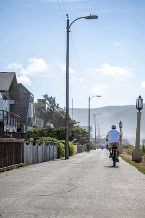 Elderly amateur men in summer clothes travel on the mountain bicycles on the footpath along the foggy Northwest Pacific Ocean preferring an active healthy lifestyle tempering the body in any weatherの写真素材