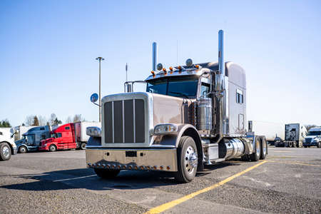 American idol coffee with milk big rig classic stylish semi truck tractor with extended long cab and chrome parts standing along on truck stop parking lot with another semi trucks and trailersの写真素材
