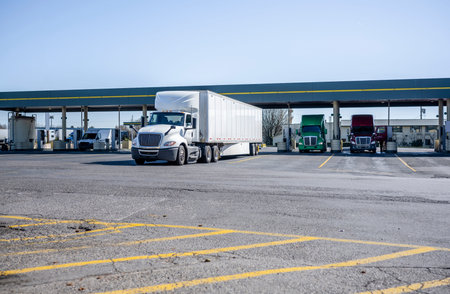 Industrial big rigs semi trucks and semi trailers standing on the truck stop parking lot taking a...