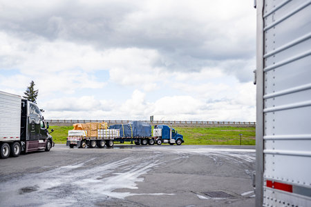 Industrial standard loaded big rig semi trucks with flat bed and refrigerator semi trailers going on...