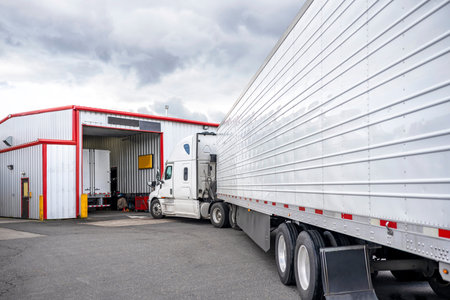 Industrial standard white big rig semi truck tractor with refrigerator semi trailer standing in line...