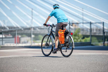 A man on a bike pedals a bicycle on a dedicated path for cyclists preferring an active healthy lifestyle using cycling ride and cycle as an alternative environmentally friendly transportationの写真素材