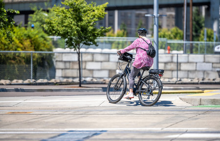 Slender woman on a bike rides a bicycle along the concrete city sidewalk  preferring an active...
