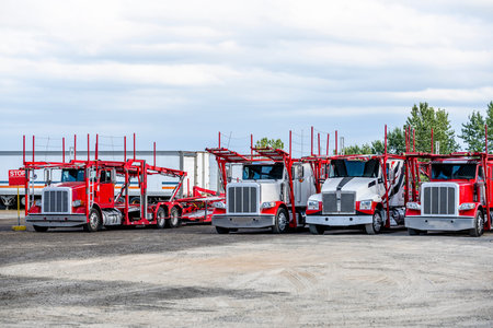 Bright red and white industrial standard big rigs car haulers semi trucks with empty modular...