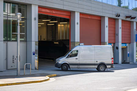 Industrial standard for local deliveries and short haul freights or small business services compact white mini van turning to building parking garage entrance for goods delivery and unloadsの写真素材