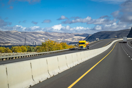 Industrial big rig yellow semi truck tractor with low cab transporting cargo in tank semi trailer...