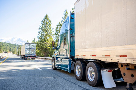 Industrial long hauler big rigs semi truck tractors with high cabs for truck driver rest transporting commercial cargo in different semi trailers driving in convoy on the highway road at sunny dayの写真素材