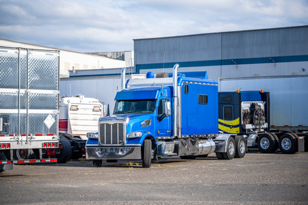 General logistic transportation different long haulers big rigs semi trucks with semi trailers standing in row on truck stop parking lot for truck driver rest waiting for the continuation freightsの写真素材