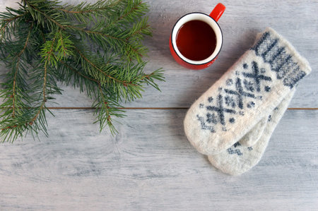 warm mittens on the wooden floor with a Christmas tree