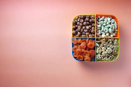 plate with nuts orange on a yellow background hazelnuts walnuts cashews dried apricotsの写真素材