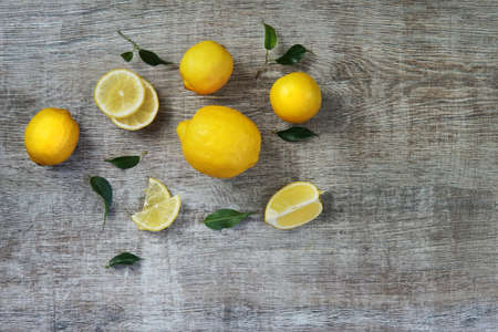 Fresh lemons and lemons leaves on rustic wooden background. Fresh lemons and lemon slice on wooden table with flat lay.の写真素材