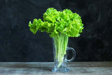 a bouquet of lettuce leaves and on a dark background in a glass on the table healthy food