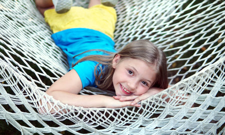 girl smiles on a hammock in summer. the concept of the summer of childhood happiness