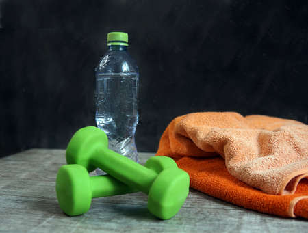dumbbell towel and bottle of water on the table image of a sporty lifestyleの写真素材