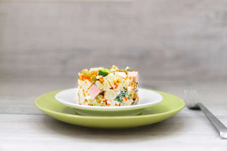 Russian traditional salad olivier on green plate and wooden tableの写真素材